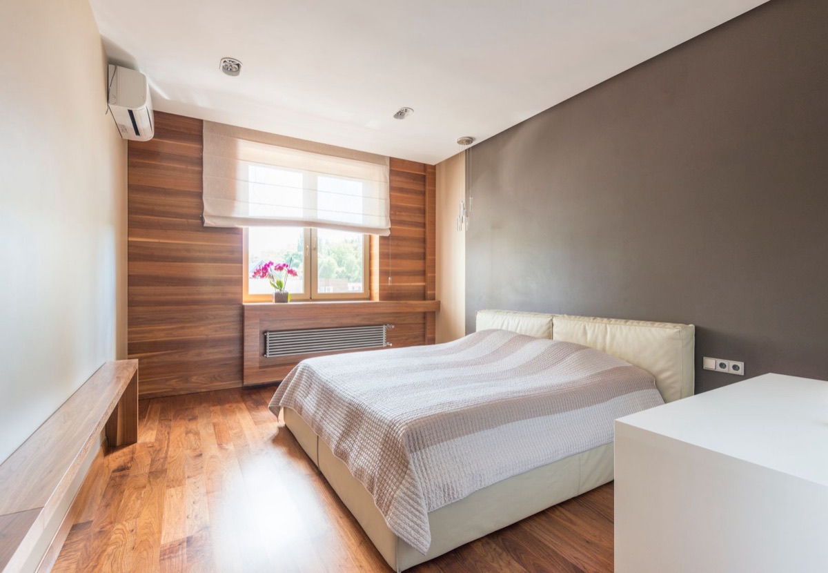 A long, narrow bedroom as it was photographed, the bed against the grey wall